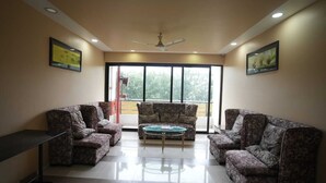 A room with two patterned sofas, a small round table, and a ceiling fan. - Hotel Grand Ashwin Executive - Igatpuri (Igatpuri)