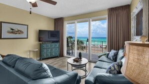 A living room with a view of the ocean, a ceiling fan, a television, and a sofa. - * Majestic Sun A204 | Gulf Views | Heated Pools * (Miramar Beach)