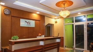 A reception desk with a wooden finish, a clock, and a sign with a logo. - VS Cube Estancia (Yercaud)