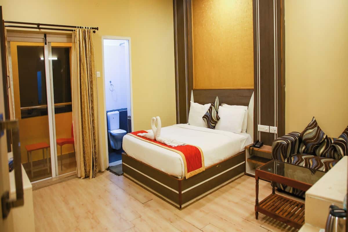 A hotel room with a bed, a sofa, a coffee table, and a bathroom visible through a sliding door.