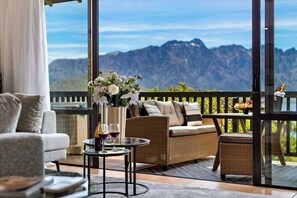 Ein Balkon mit Korbmöbeln, einem Blumenstrauß und einem Tisch mit Weingläsern.