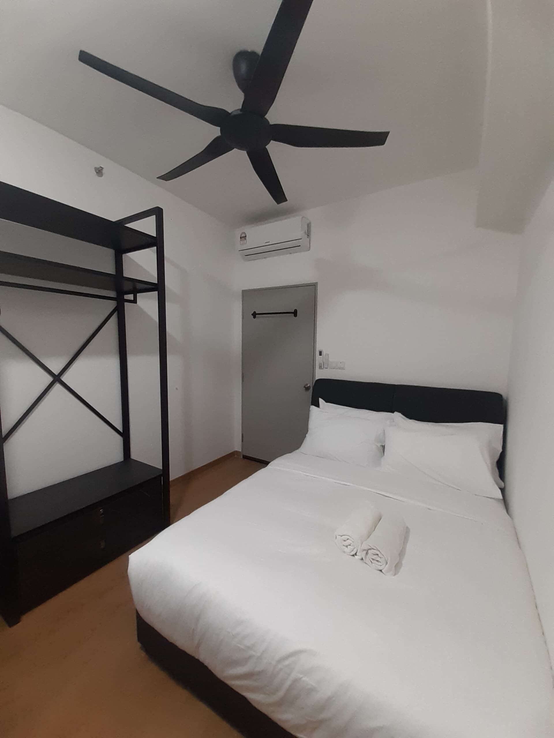 A room with a bunk bed, a single bed, a ceiling fan, and an air conditioning unit.