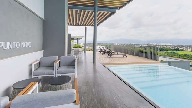 A modern outdoor pool area with lounge chairs and a view of the city.