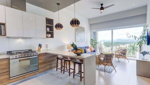 A modern kitchen with a central island, bar stools, and a dining area with wicker chairs.