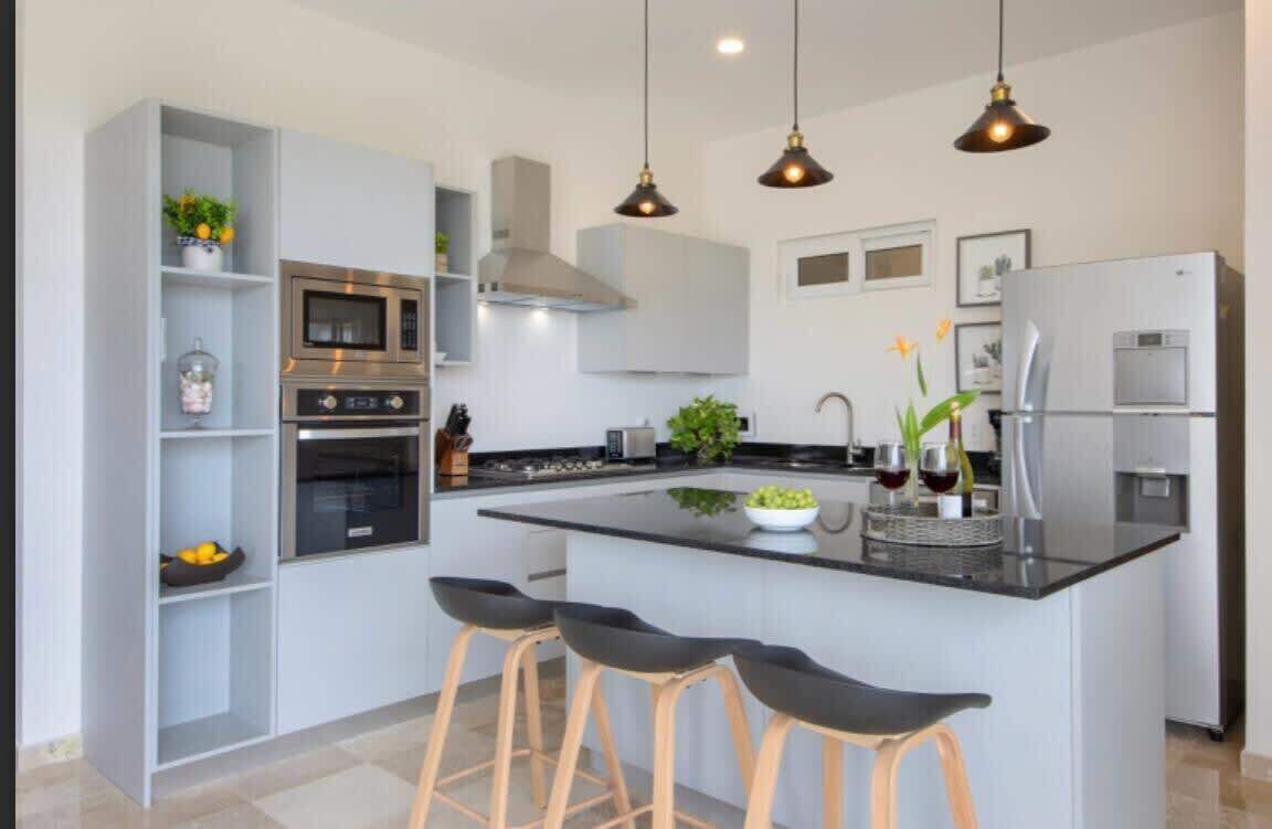 A modern kitchen with a central island, bar stools, built-in appliances, and pendant lighting.