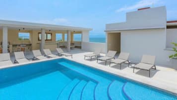 Une piscine avec des chaises longues et vue sur la mer.