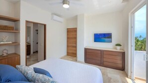 Ein Schlafzimmer mit Bett, Deckenventilator, Fernseher und Blick ins Freie.