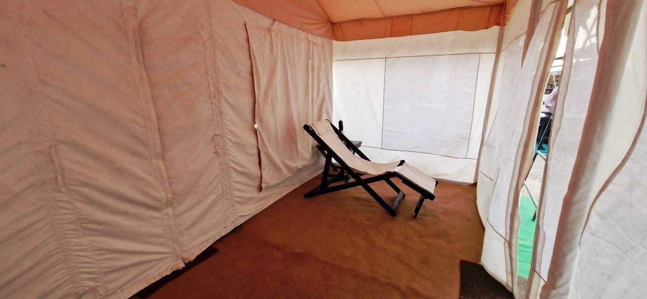 Une pièce aménagée comme une tente, avec un seul fauteuil inclinable, une fenêtre et une vue sur l’extérieur.