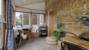 Une pièce chaleureuse avec un mur en pierre, des meubles en osier et une table en bois.