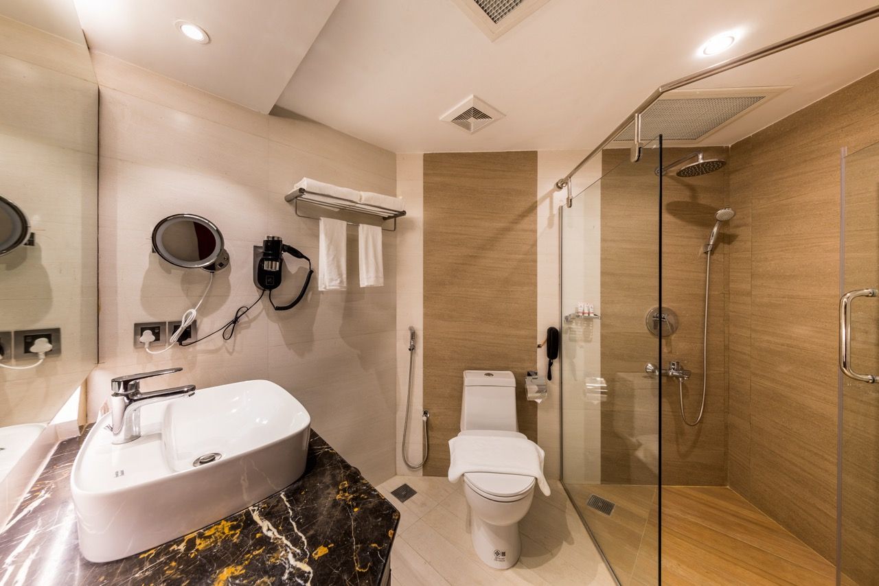 A modern bathroom with a marble sink, a toilet, and a glass-enclosed shower.