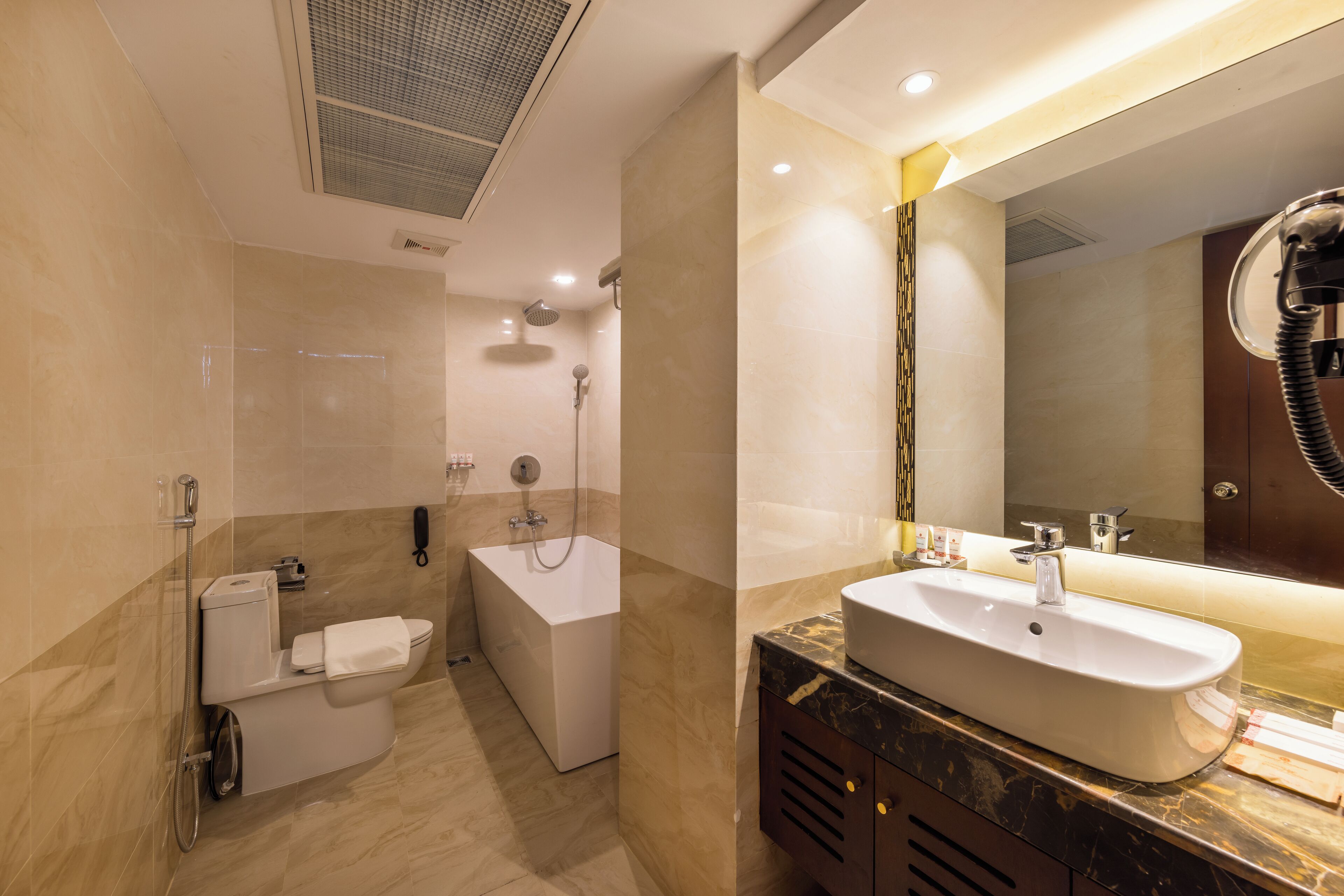 A modern bathroom with a bathtub, a toilet, a sink, and a large mirror.