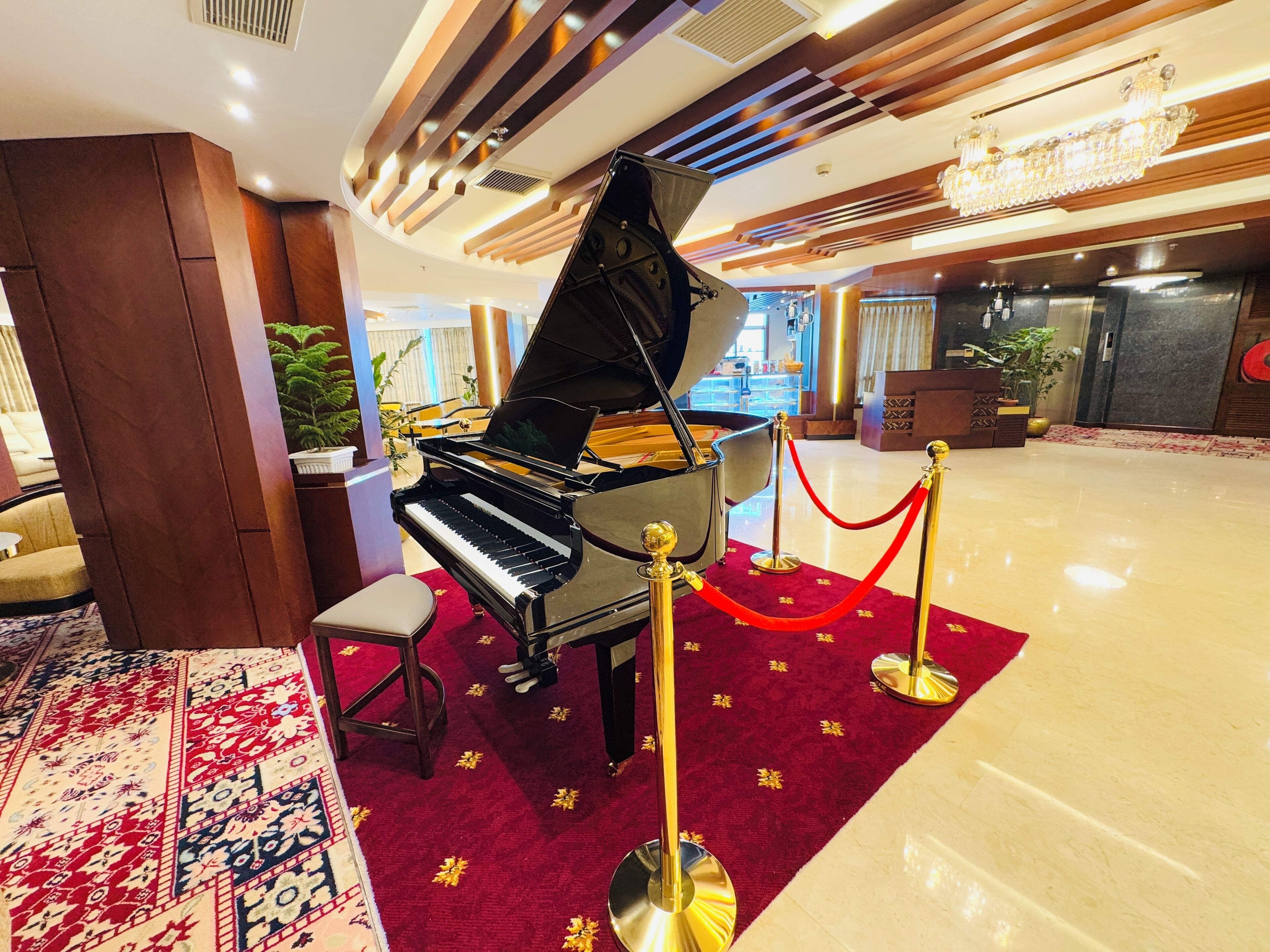 Un pianoforte a coda in un atrio con tappeto rosso e colonne dorate.