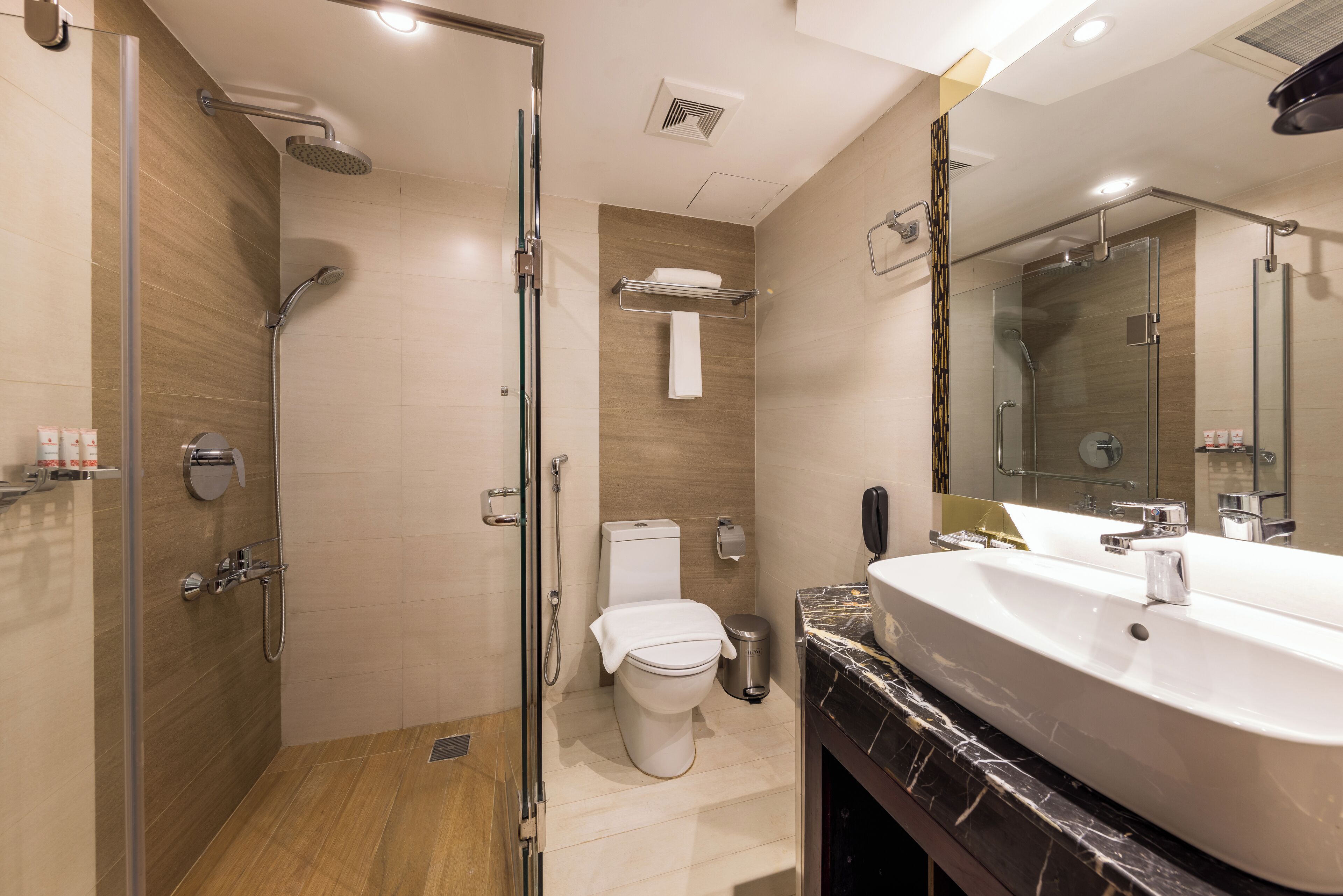 A modern bathroom with a glass-enclosed shower, a white toilet, and a large vanity with a mirror.