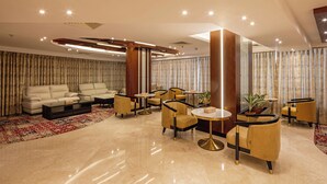 Un lobby moderno con un sofá, sillones y mesas redondas.