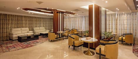 Un hall d’entrée moderne avec un canapé, des fauteuils et des tables rondes.