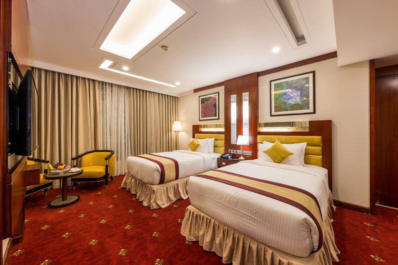 A hotel room with two beds, a television, a desk, and a chair.