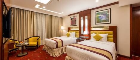 A hotel room with two beds, a television, a desk, and a chair.