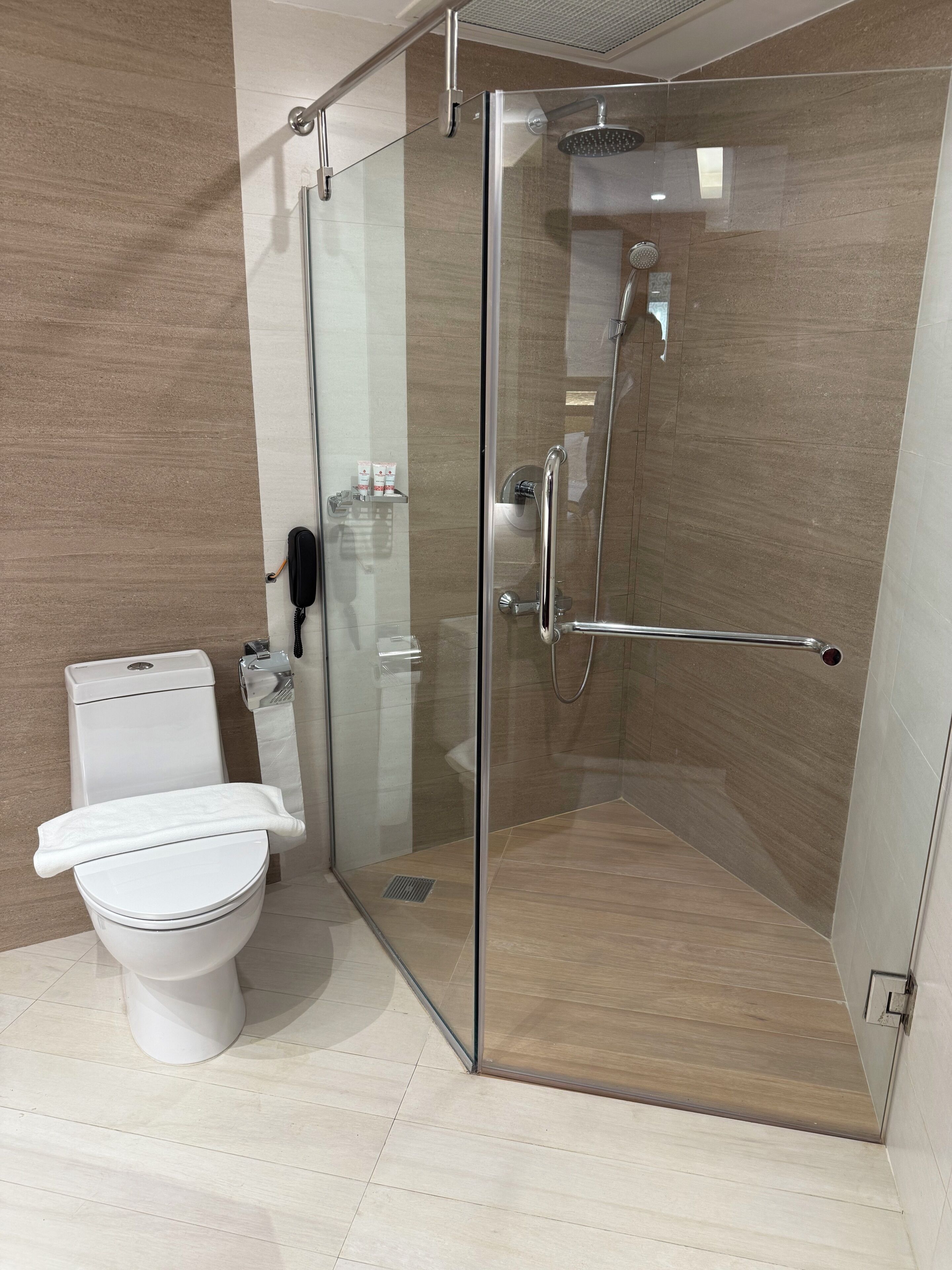 Un baño moderno con ducha de vidrio, inodoro y secamanos.