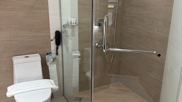 Un baño moderno con ducha de vidrio, inodoro y secamanos.