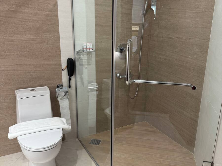 Un baño moderno con ducha de vidrio, inodoro y secamanos.