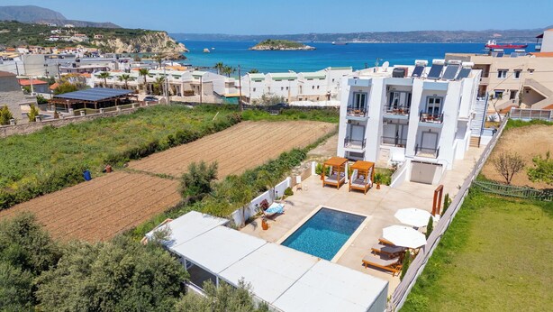 Un hotel moderno con piscina en la azotea, mobiliario exterior y vistas al mar.