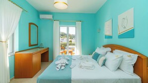 Un dormitorio con cama, cómoda de madera, espejo, ventana con cortinas y obras de arte en las paredes.