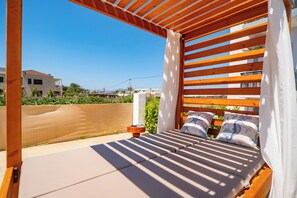 A wooden pergola with a bed, white curtains, and a view of buildings in the background. - Christianna Apartments 1 -Vacation apartment in Crete (Vámos)