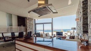 A modern kitchen with a large island, a stone wall, and a view of the sea. - Villa Kera Panorama - villa with pool, Crete (Vámos)