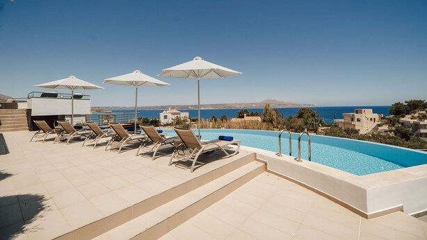 A poolside area with lounge chairs and umbrellas, overlooking a clear blue sea and distant hills. - Villa Kera Panorama - villa with pool, Crete (Vámos)