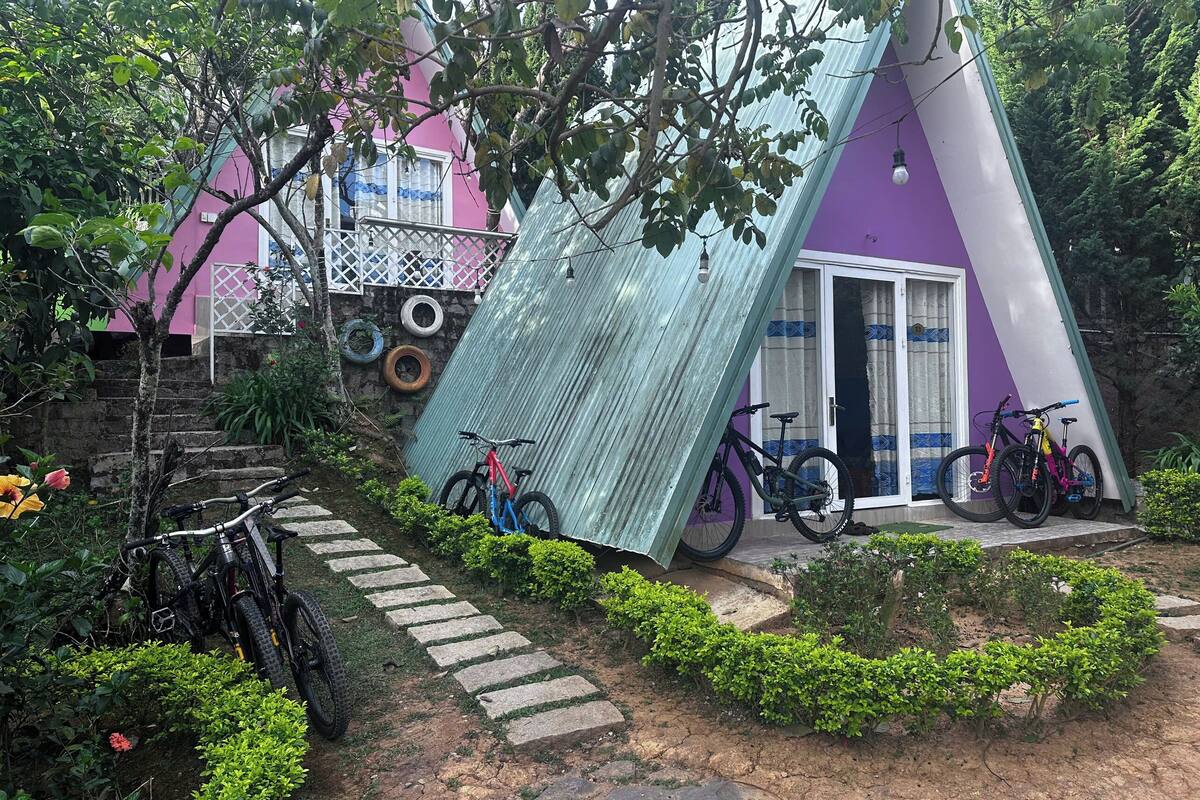 A colorful house with a sloped roof, bicycles parked outside, and a stone pathway leading to the entrance.