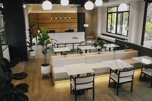 A modern cafe with white furniture, large windows, and indoor plants. - Hotel Whitt Hua Hin (Hua Hin)