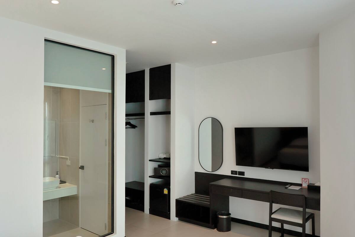 Ein modernes Hotelzimmer mit einem Bett, einem Schreibtisch, einem Fernseher und einem begehbaren Kleiderschrank.