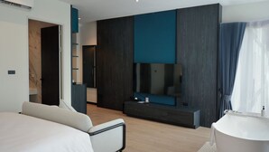 Ein modernes Hotelzimmer mit einem großen Bett, einer Sitzecke, einem Fernseher, einem Konsolentisch und einer Badewanne.