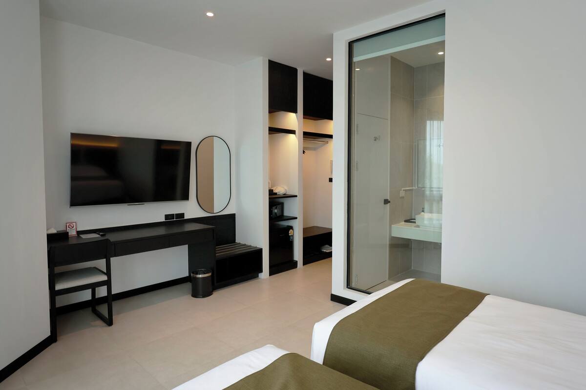 Ein modernes Hotelzimmer mit Bett, Schreibtisch, Fernseher und begehbarem Kleiderschrank.
