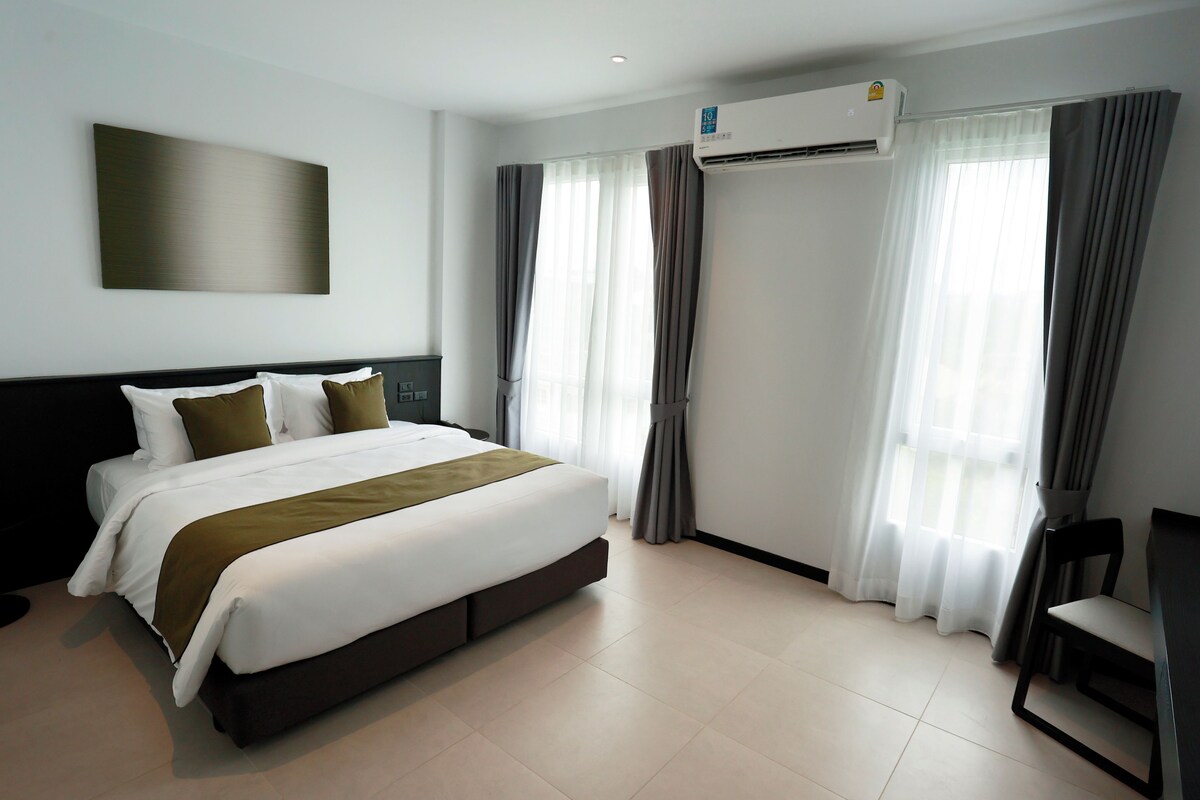 Une chambre d’hôtel moderne dotée d’un grand lit, de la climatisation, de rideaux et d’un bureau.
