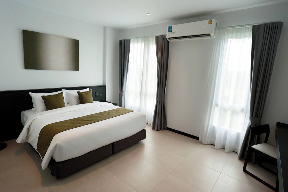 Ein modernes Hotelzimmer mit einem großen Bett, Klimaanlage, Vorhängen und einem Schreibtisch.