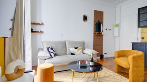 En moderne stue med sofa, sofabord, lænestol i gult og en dekorativ vase.