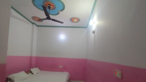 Een slaapkamer met een bed, een plafondventilator en een lamp.
