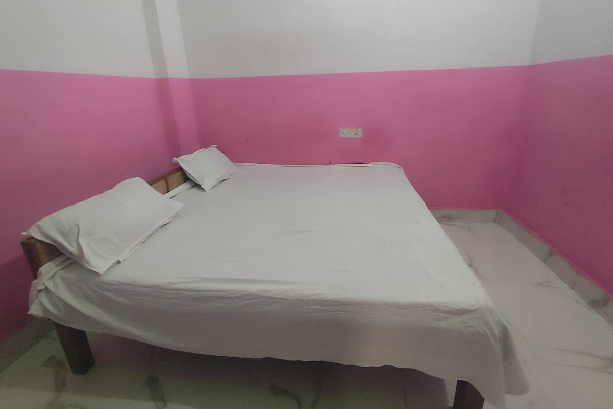 Una cama individual en una habitación con paredes rosas y suelo blanco.
