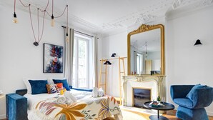 Ein modernes Hotelzimmer mit einem Bett, einem blauen Sessel, einem Kamin und einem großen Spiegel.
