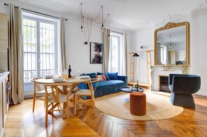 A modern living room with a wooden dining table, blue sofa, and a fireplace.