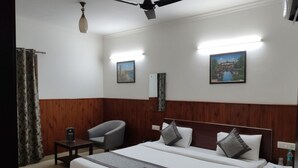A hotel room with a large bed, two bedside tables, a chair, a ceiling fan, and two wall-mounted lights. - Shri Sai Guest House - Opp Azadpur Main Mandi (New Delhi)