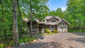 A two-story house with a front porch, stone foundation, and a garage.