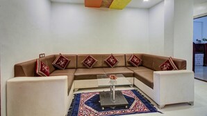 A modern living room with a brown sectional sofa, white armchairs, a glass coffee table, and a patterned rug. - Straw Bella Inn Villa (Dhangarwadi)