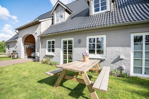 A house with a large patio table, a covered outdoor area, and a garage.