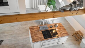 Una cocina moderna con encimera de madera, muebles blancos y estufa integrada.