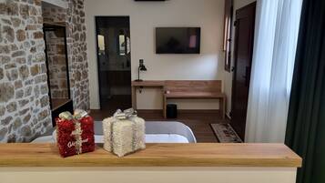 A cozy living room with a stone wall, a wooden bench, a flat-screen TV, and a small table with wrapped gifts.