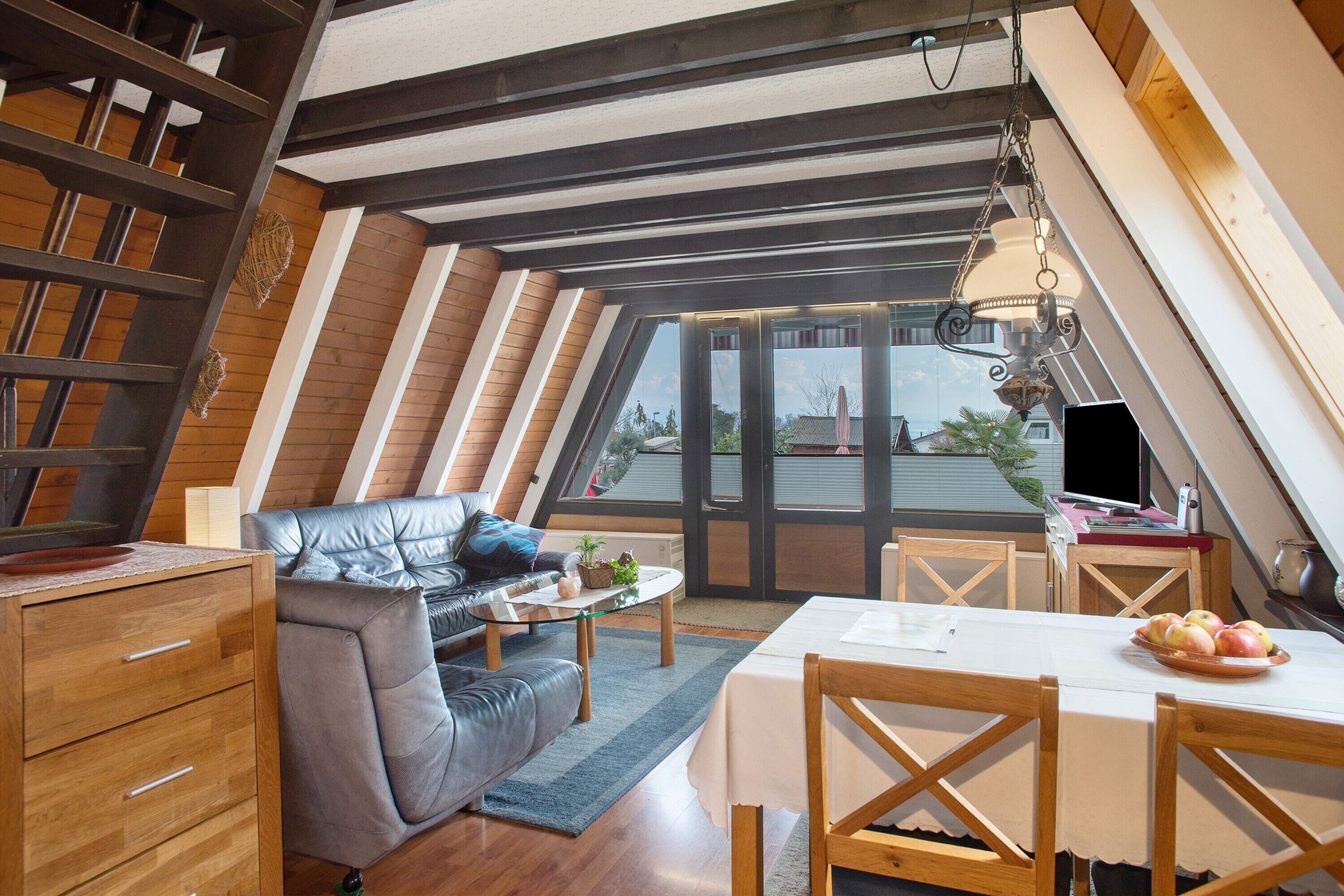 Une pièce de style loft avec un plafond en pente, un canapé, une table à manger et un téléviseur.