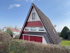 Una casa con techo inclinado, fachada roja y antena parabólica.
