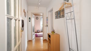Ein Korridor mit einem Holzschrank, einer Metallleiter und einer Tür mit einem Telefon.